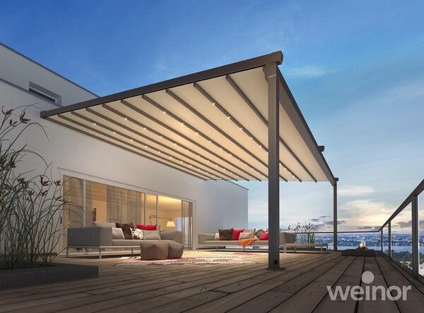 Moderne Terrassenüberdachung mit LED-Beleuchtung auf stilvoller Dachterrasse bei Sonnenuntergang.
